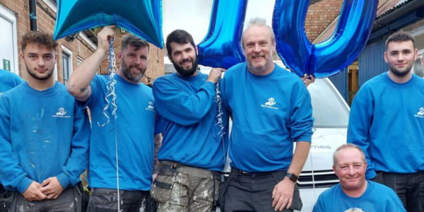 safe and healthy homes team in their blue branded t-shirts with a 10th anniversary blue above