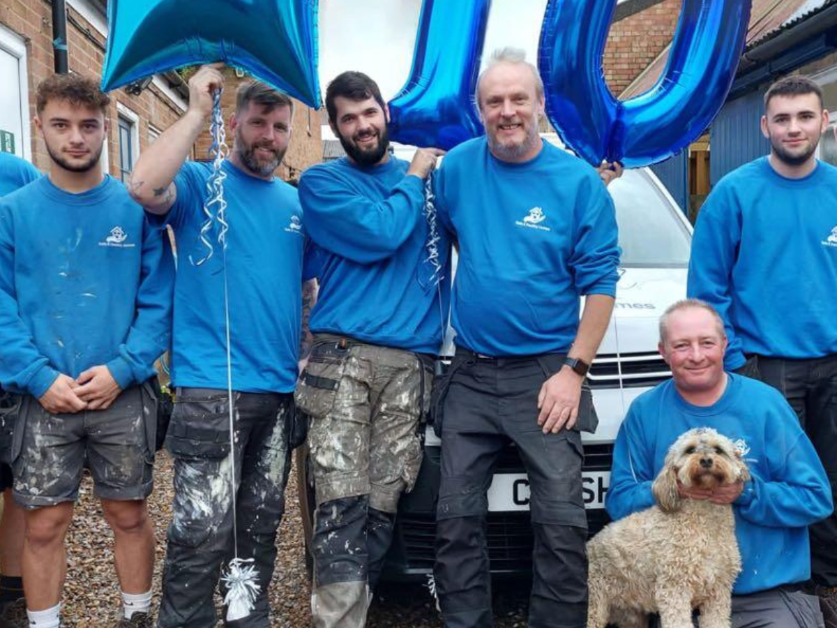 safe and healthy homes team in their blue branded t-shirts with a 10th anniversary blue above