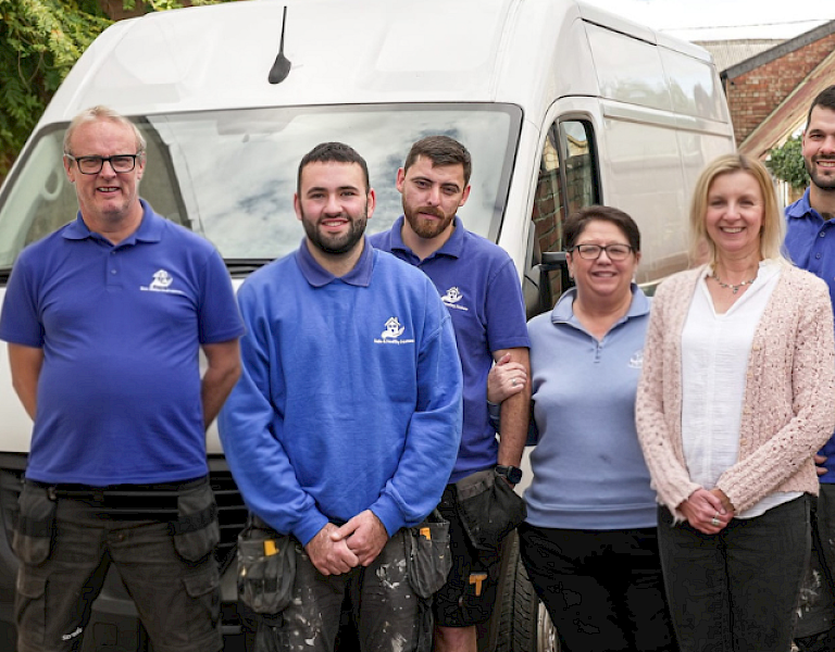 safe and healthy homes team in their blue branded t-shirts with a 10th anniversary blue above