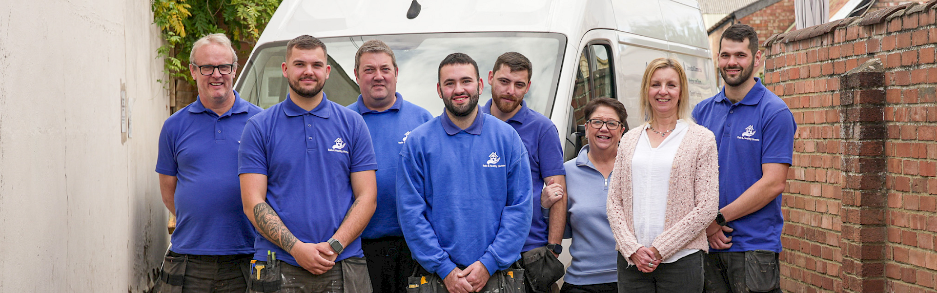 safe and healthy homes team in their blue branded t-shirts with a 10th anniversary blue above