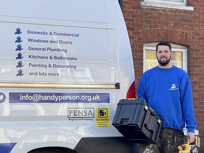 A handyperson stands beside a van filled with tools, ready for a day of repairs, home improvements and property maintenance work