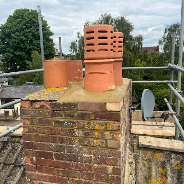 Chimney repair work in progress on a brick chimney stack with terracotta pots, surrounded by scaffolding, ideal for roof and chimney maintenance services