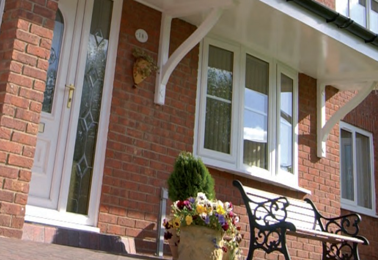 red brick house featuring white windows and a white door