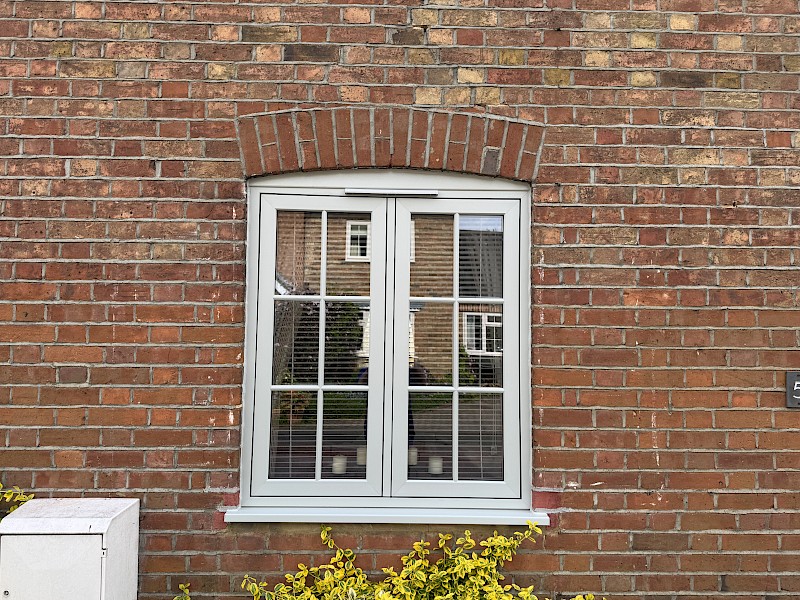 Handyperson in reflection of recently fitted new white double glazed windows