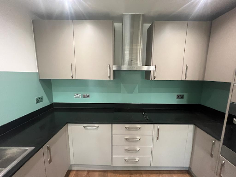 Stylish kitchen with black countertops and green walls, highlighting recent repairs and replacement worktops