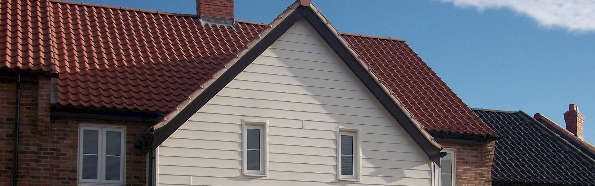 house featuring a red roof, showcasing roofline facias, soffits, and guttering services