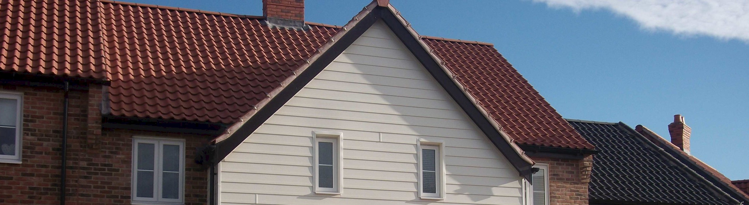 house featuring a red roof, showcasing roofline facias, soffits, and guttering services