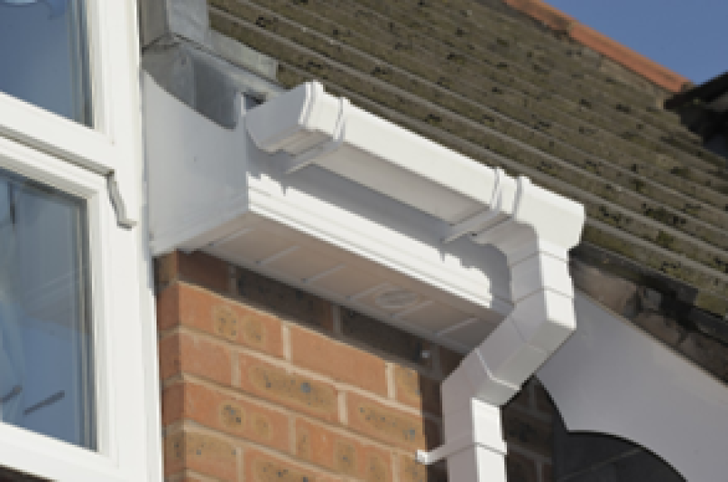 Close-up view of a house gutter, showcasing roofline facias and soffits, highlighting guttering work