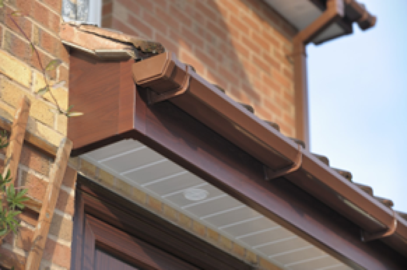 brown and white gutter installed on a house, showcasing roofline facias and soffits for enhanced drainage services