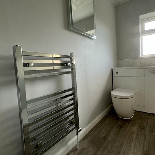 clean bathroom scene displaying a toilet, sink, and towel rack, emphasizing installation and repair features