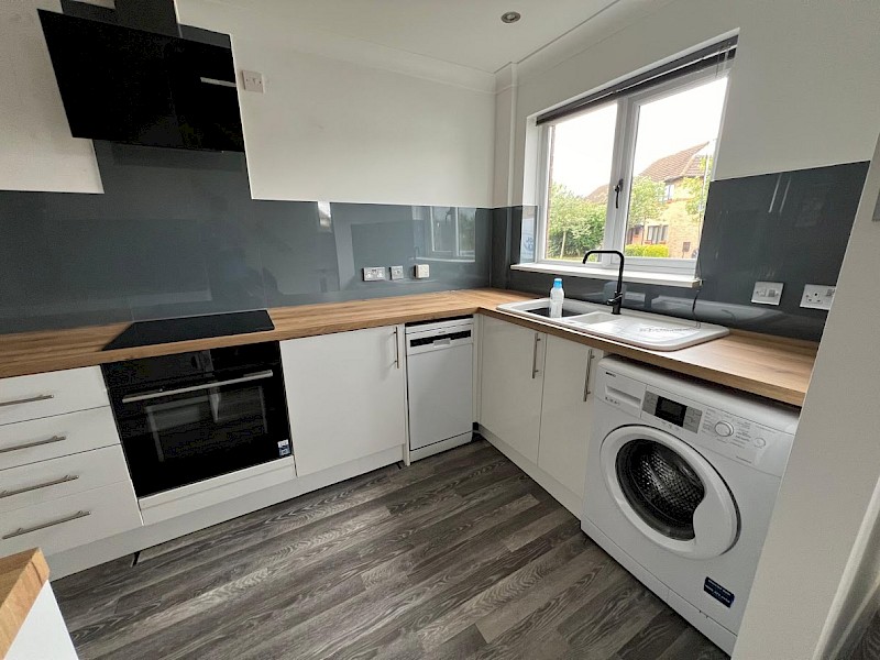 well-equipped kitchen with a washing machine, sink, and oven, highlighting new installations and fresh paint