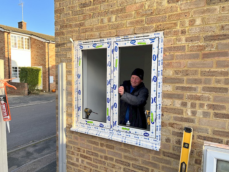 Handyperson in reflection of recently fitted new white double glazed windows